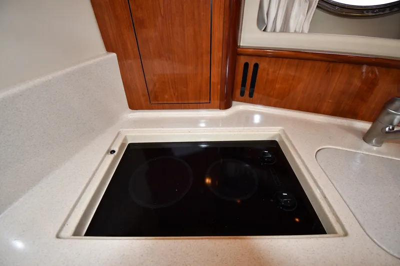 Slide: The Image of 2004 Sea Ray 420 Sundancer kitchen with sleek cooktop and wooden cabinetry. - 39