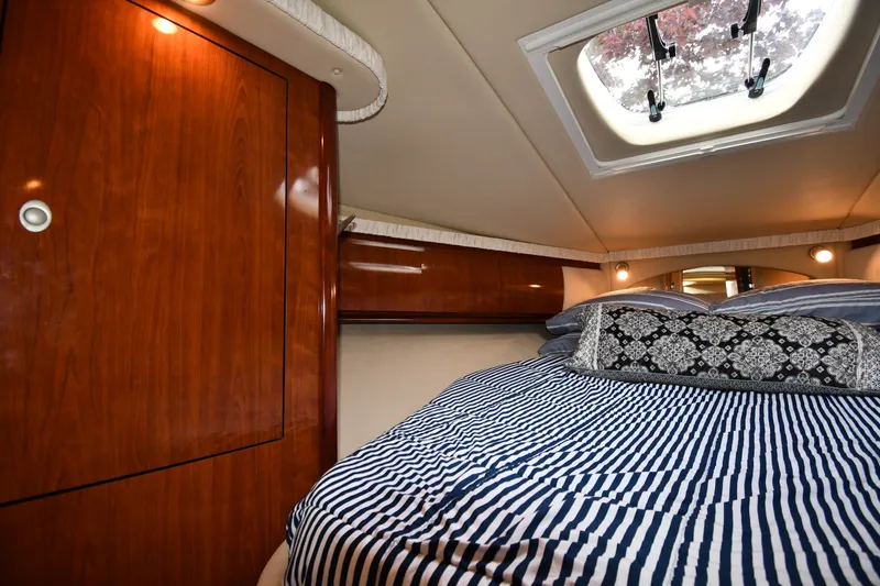 Slide: The Image of Luxurious cabin interior of 2004 Sea Ray 420 Sundancer with striped bedding and wood paneling. - 28