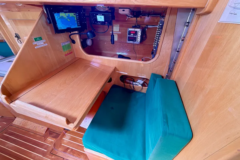 Slide: The Image of Navigation station inside 2007 Chuck Burns Custom 49 Schooner, featuring wooden desk and green cushioned seat. - 11