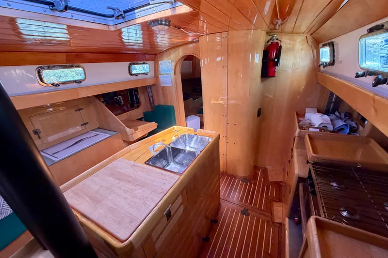 Slide: The Image of Interior of 2007 Chuck Burns Custom 49 Schooner with wooden finishes and compact kitchen area. - 15