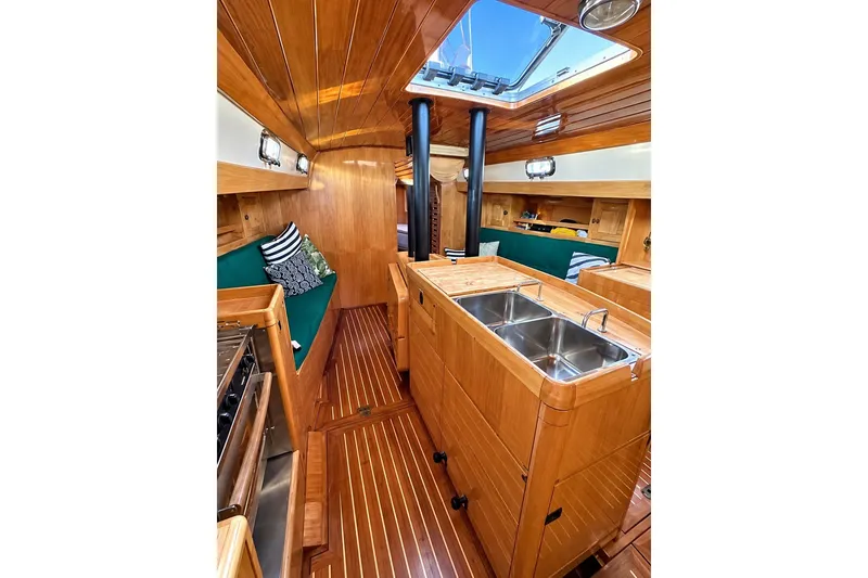 Slide: The Image of Interior of 2007 Chuck Burns Custom 49 Schooner with wooden finishes and green seating. - 17