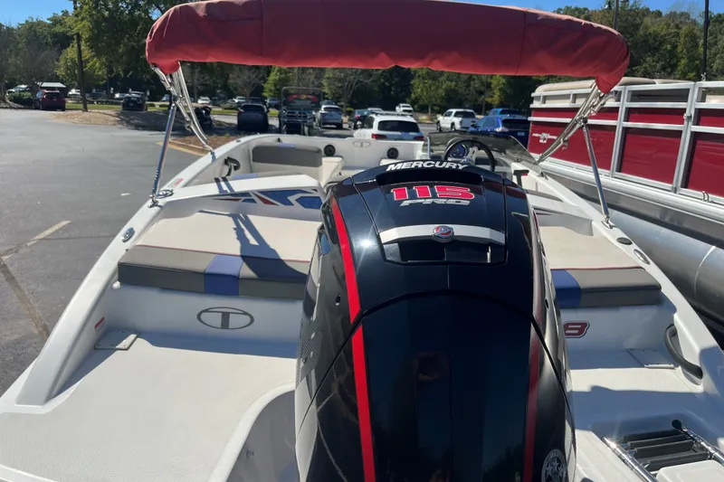 Slide: The Image of 2022 Tahoe T18 boat with Mercury 115 engine, parked outdoors under a red canopy. - 2