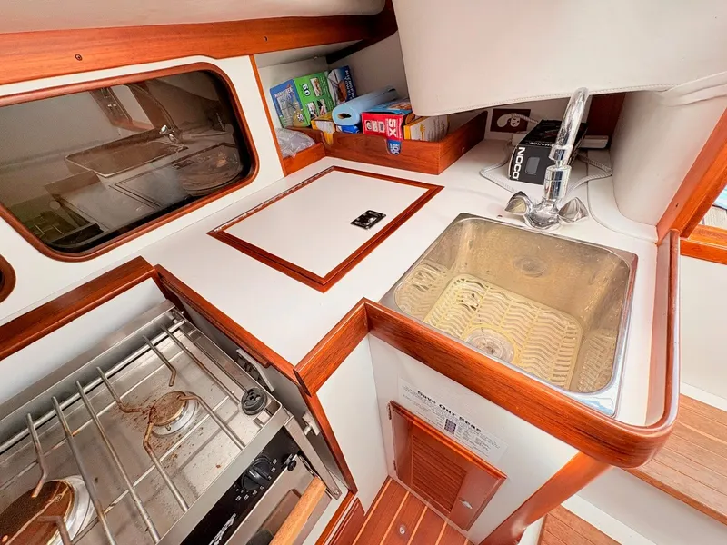Slide: The Image of The galley of a 2009 Alerion Express 38 with a sink, stove, and storage space. - 16