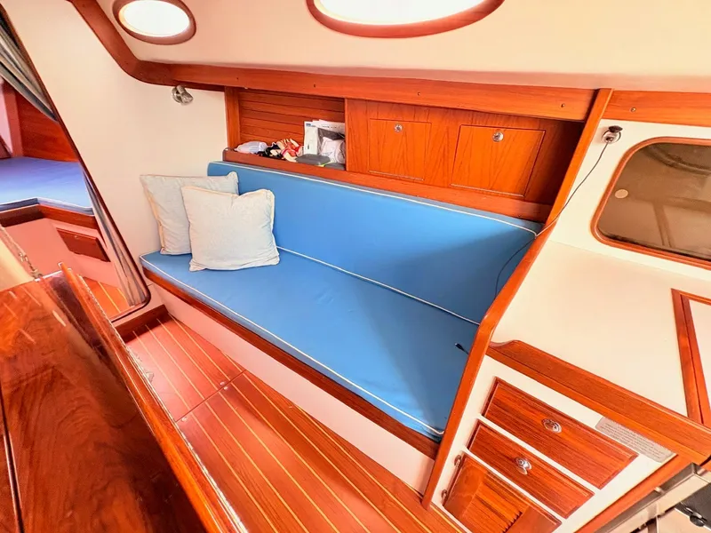 Slide: The Image of The cabin of a 2009 Alerion Express 38 features a blue bench seat and wooden furnishings. - 9