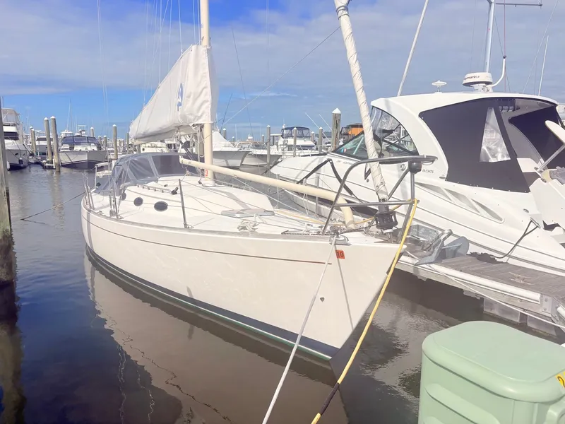 Slide: The Image of A white sailboat docked at a marina, surrounded by other boats in the harbor. - 2