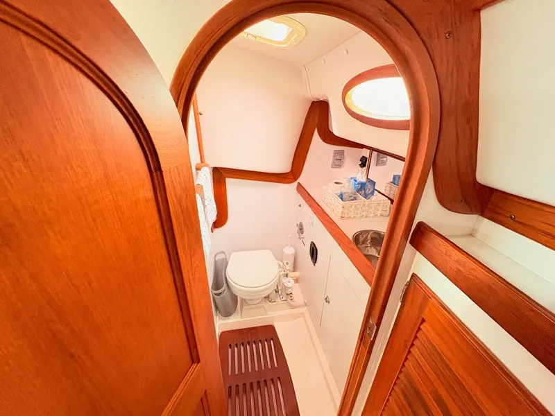 Slide: The Image of The image shows the bathroom of a 2009 Alerion Express 38 with wood paneling and a porthole. - 13