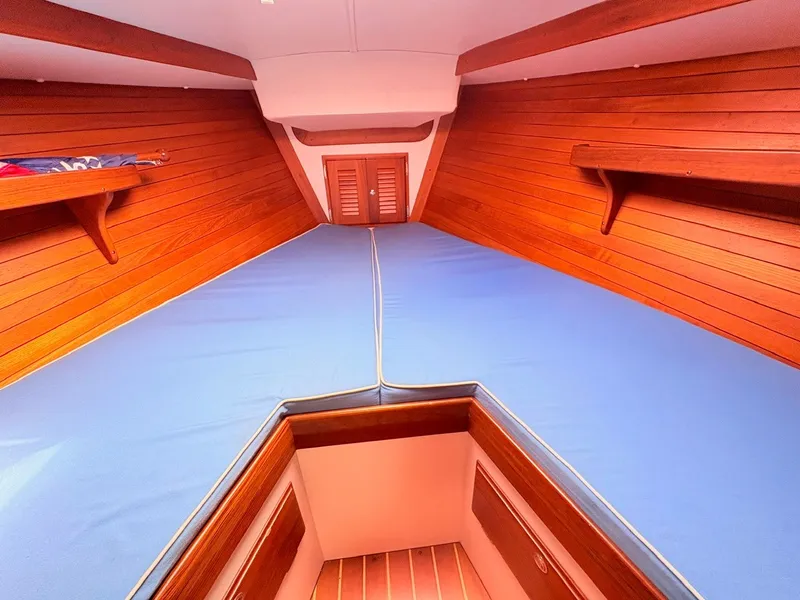 Slide: The Image of The cabin of a 2009 Alerion Express 38 with blue cushions and wooden paneling. - 19