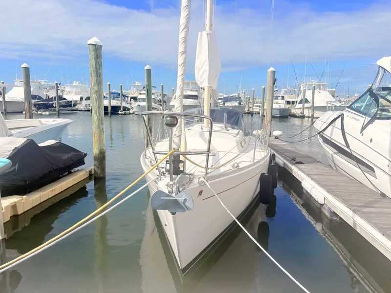 Slide: The Image of A white sailboat docked in a calm marina, surrounded by other boats and piers. - 1
