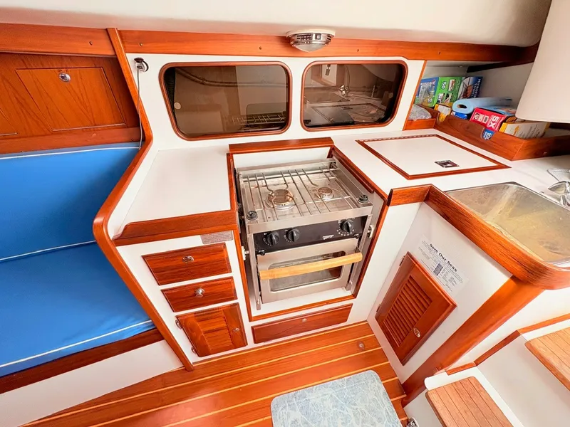 Slide: The Image of Interior view of a 2009 Alerion Express 38, featuring a compact kitchen with stove and sink. - 14