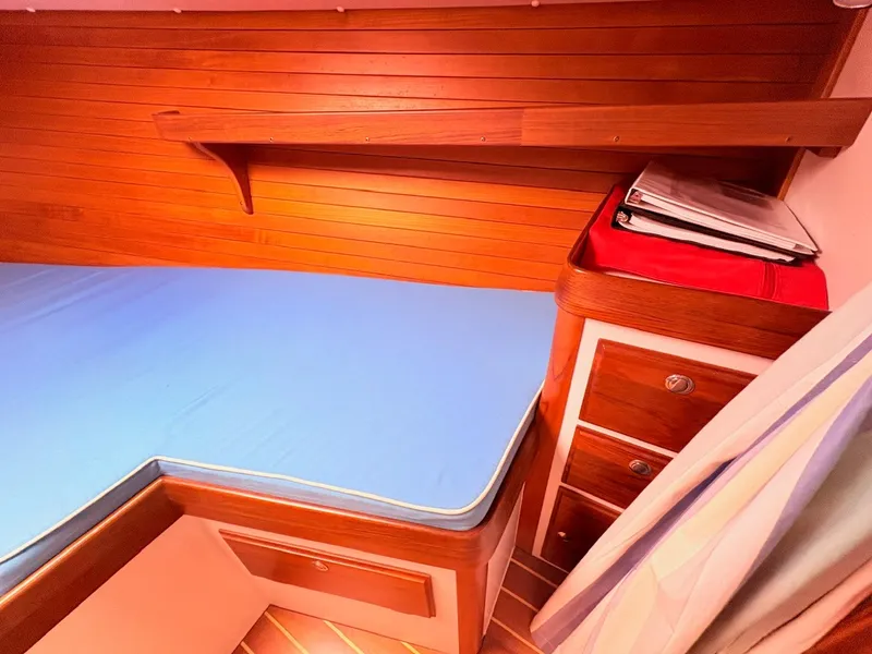 Slide: The Image of The cabin of a 2009 Alerion Express 38 with wood paneling and a blue mattress. - 18