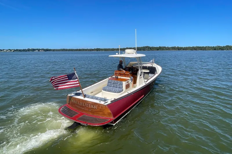 Slide: The Image of 2004 Hinckley Talaria 29C boat cruising on a sunny lake with American flag. - 3