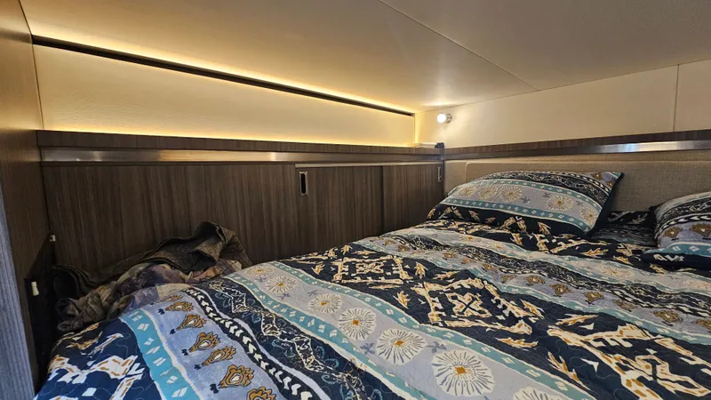 Slide: The Image of The cabin of the 2024 Sea Ray Sundancer 320 Outboard features a cozy bed with patterned blankets. - 30