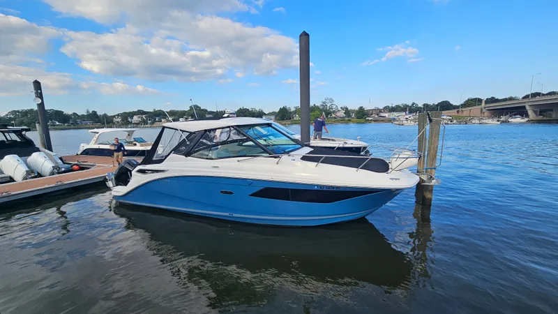 Slide: The Image of A 2024 Sea Ray Sundancer 320 Outboard is docked in the water. The sky is blue. - 4