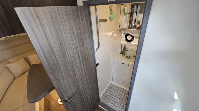 Slide: The Image of Interior view of a 2024 Sea Ray Sundancer 320 Outboard with a modern bathroom and wooden doors. - 26