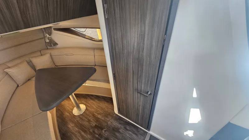 Slide: The Image of Interior of a 2024 Sea Ray Sundancer 320 Outboard with a cozy seating area and wooden table. - 25