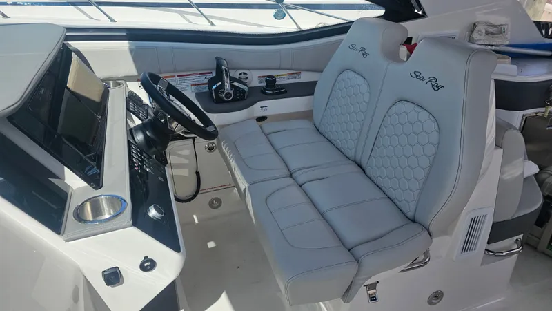Slide: The Image of The image shows the cockpit of a 2024 Sea Ray Sundancer 320 Outboard with sleek, cushioned seats and a modern helm. - 16