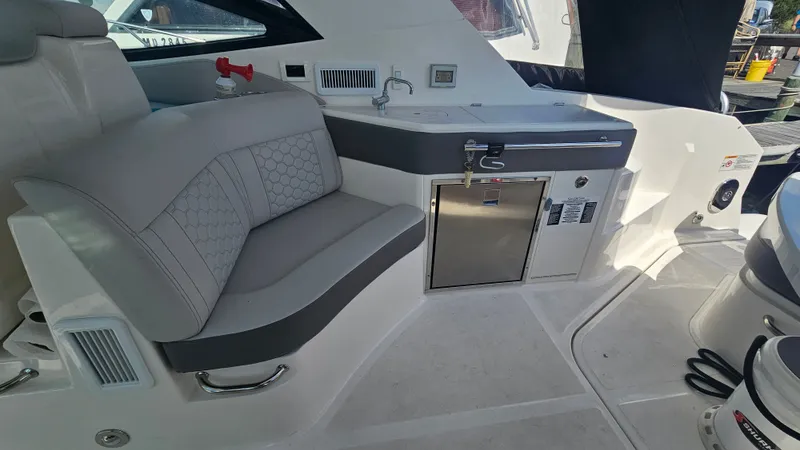 Slide: The Image of The 2024 Sea Ray Sundancer 320 Outboard features an elegant seating area with gray upholstery and a compact kitchenette. - 10