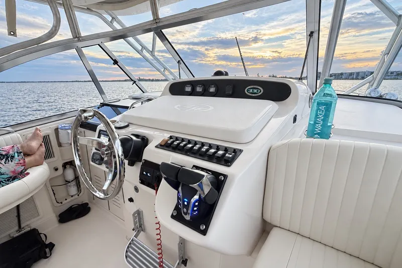 Slide: The Image of 2008 Grady-White Express 330 boat interior with steering wheel, controls, and ocean view at sunset. - 22