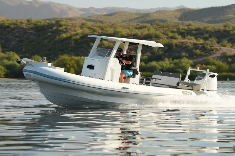 Slide: The Image of 2027 Tide Craft 26 Capri boat cruising on a scenic lake with mountains in the background. - 1