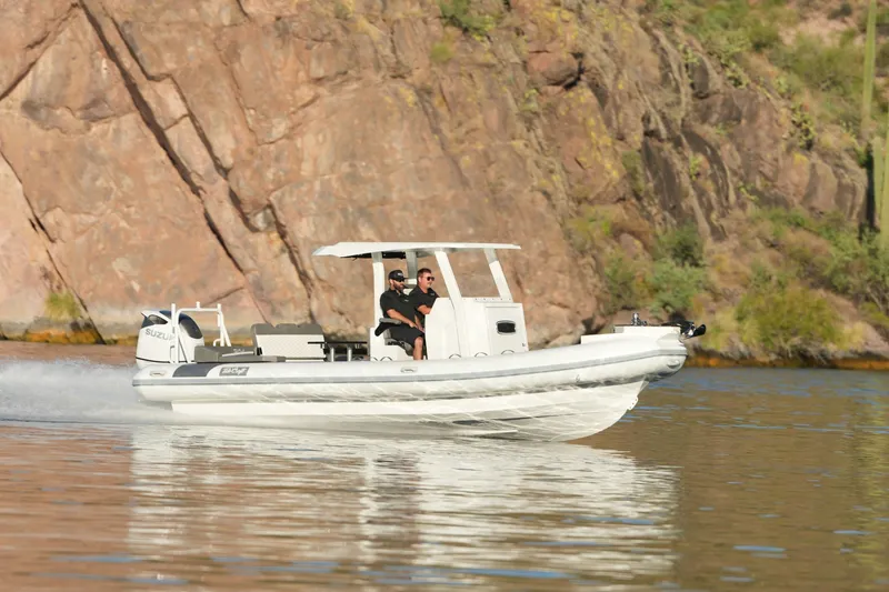 Slide: The Image of 2027 Tide Craft 26 Capri boat cruising on a scenic lake with rocky backdrop. - 0