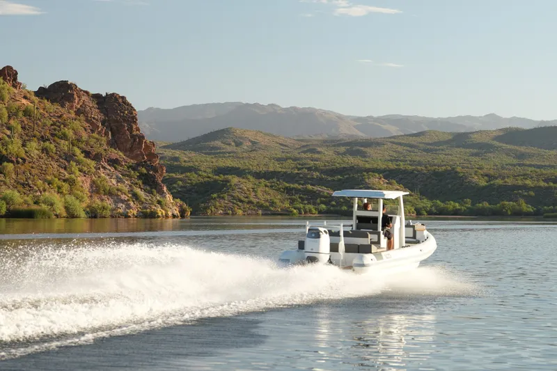 Slide: The Image of 2027 Tide Craft 26 Capri boat cruising on a scenic lake with mountainous backdrop. - 9