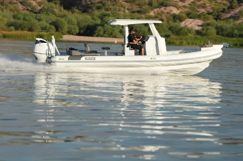 Slide: The Image of 2027 Tide Craft 26 Capri boat cruising on a serene lake with lush greenery. - 11