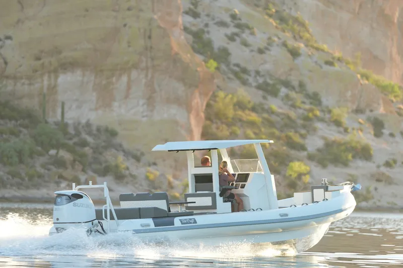 Slide: The Image of 2027 Tide Craft 26 Capri boat cruising on a scenic lake with rocky cliffs. - 12