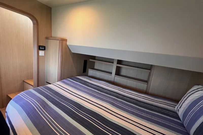 Slide: The Image of Interior cabin of 2018 Aquila 44 Yacht with striped bedding and wooden accents. - 37
