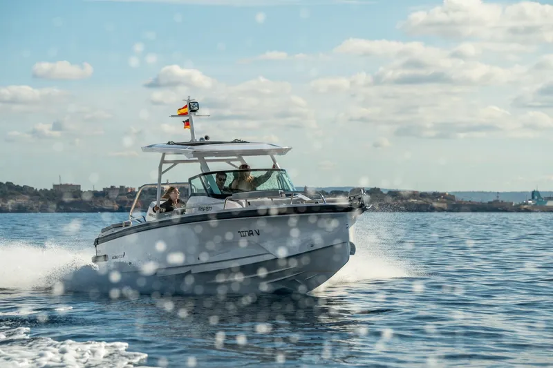 Slide: The Image of 2027 Axopar 29 Sun-Top boat cruising on open water under a clear sky. - 2
