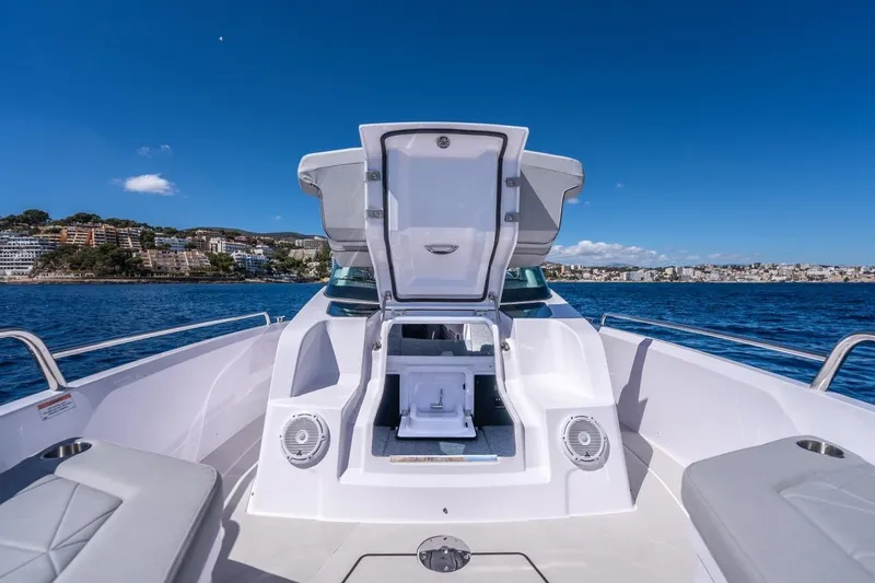 Slide: The Image of 2027 Axopar 29 Sun-Top boat with open storage, scenic coastal view. - 12