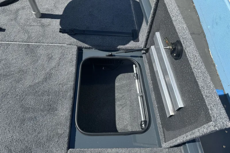 Slide: The Image of Open storage compartment in 2027 Ranger RT198P boat, featuring carpeted interior and latch mechanism. - 12