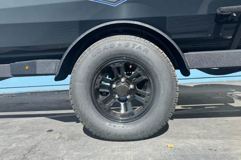 Slide: The Image of 2027 Ranger RT198P trailer tire with black alloy wheel on pavement. - 2