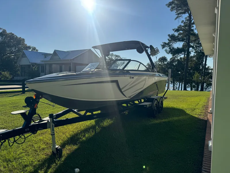 Slide: The Image of A white 2018 Tigé R23 boat on a trailer, parked on grass beside a house. - 5