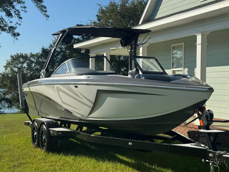 Slide: The Image of A 2018 Tigé R23 boat on a trailer in front of a house. - 1