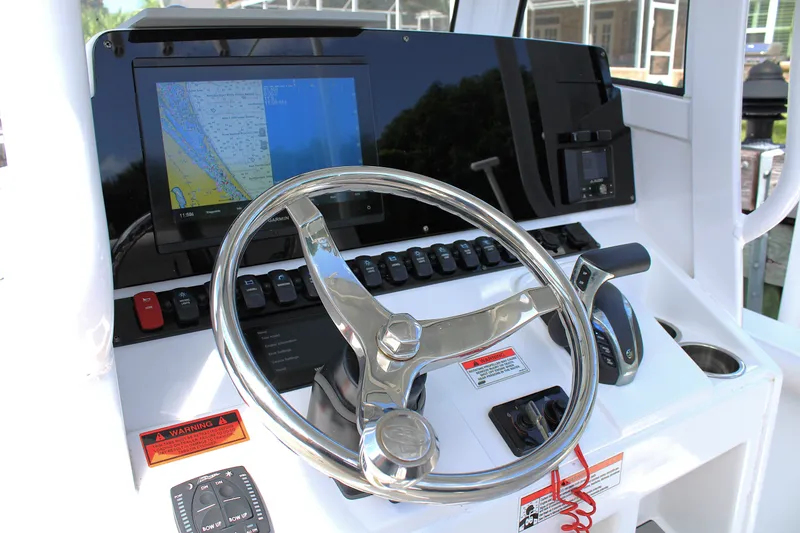 Slide: The Image of 2022 Sea Hunt BX25FS boat dashboard with steering wheel and navigation display. - 12