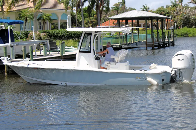 Slide: The Image of 2022 Sea Hunt BX25FS boat cruising on a sunny day near a dock. - 2