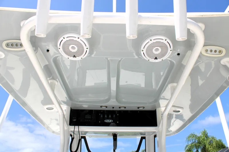 Slide: The Image of 2022 Sea Hunt BX25FS boat T-top with speakers and rod holders against blue sky. - 21