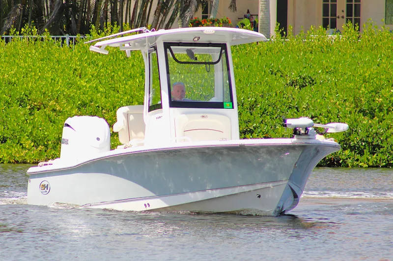 Slide: The Image of 2022 Sea Hunt BX25FS boat cruising on a calm waterway with lush greenery. - 1
