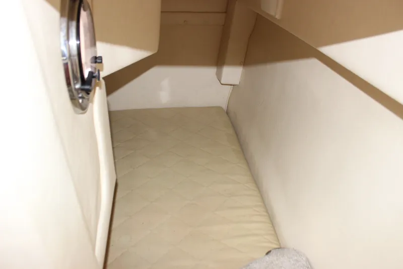Slide: The Image of 2007 Sea Ray 240 Sundancer cabin interior with beige bedding and porthole. - 19