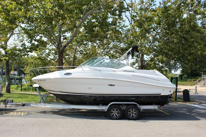 The Image of 2007 Sea Ray 240 Sundancer boat on trailer, parked near trees. - 0