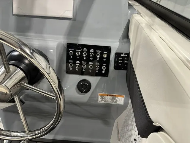 Slide: The Image of The image shows a boat's helm with a stainless steel steering wheel and a control panel with switches. - 22