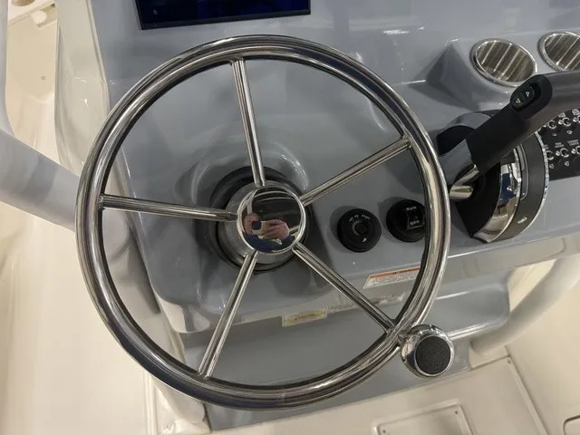 Slide: The Image of Close-up of a shiny metal steering wheel on a boat, surrounded by control knobs and holders. - 21