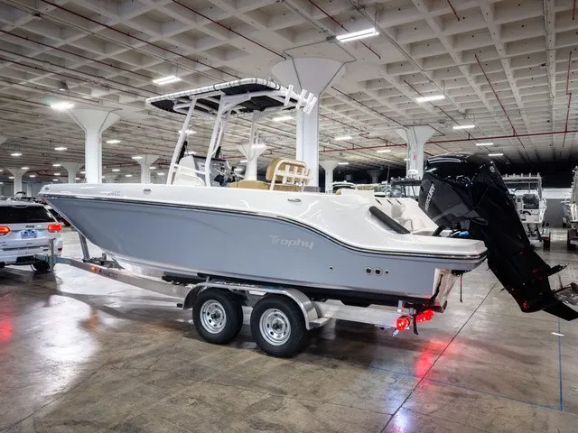 Slide: The Image of A 2025 Trophy T24CC boat on a trailer in a large indoor space. - 3