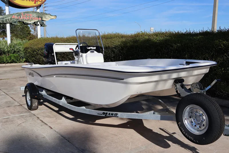 Slide: The Image of 2027 Mako Pro Skiff 17 CC boat on trailer, parked outdoors near greenery. - 4