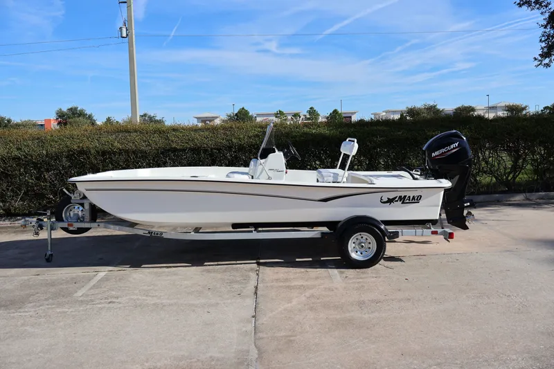 The Image of 2027 Mako Pro Skiff 17 CC boat on trailer, parked outdoors under clear blue sky. - 0
