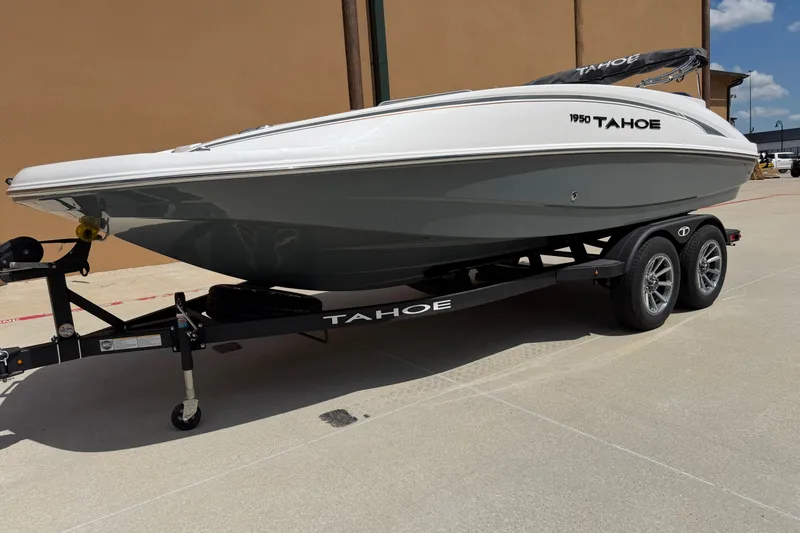 Slide: The Image of 2027 Tahoe 1950 boat on trailer, parked outdoors under clear sky. - 1