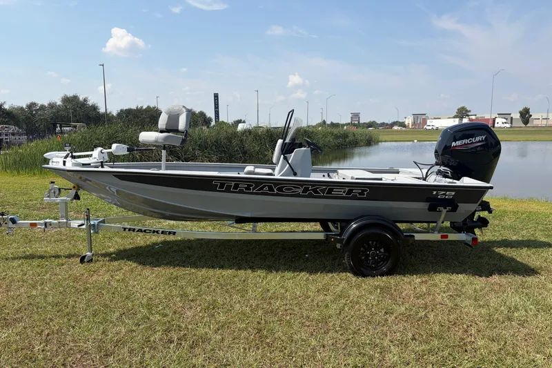 Slide: The Image of 2027 Tracker Bass Tracker 175 CC boat on trailer by a lake, featuring Mercury engine. - 35