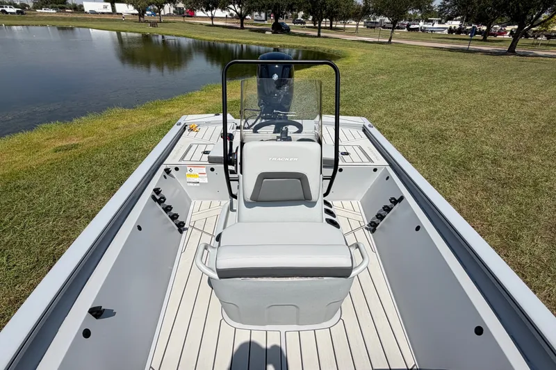 Slide: The Image of 2027 Tracker Bass Tracker 175 CC boat interior with seating and steering console near a pond. - 48
