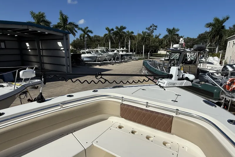 Slide: The Image of 2024 Cobia 350 Center Console boat docked, surrounded by palm trees and other boats. - 36