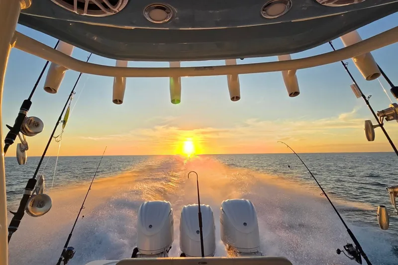 Slide: The Image of 2024 Cobia 350 Center Console boat cruising at sunset with fishing rods. - 48